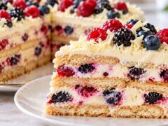 Parche biskvitena torta s krem, malini, borovinki i kapini, ukrasena s gorski plodove i strugotini ot byal shokolad.
