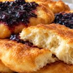 Родопски мекици с домашно сладко от боровинки Puhkavi rodopski mekitsi sas zlatista korichka i domashno sladko ot borovinki, edna mekitsa e razchupena i se vizhda mekata vazdushna sreda.